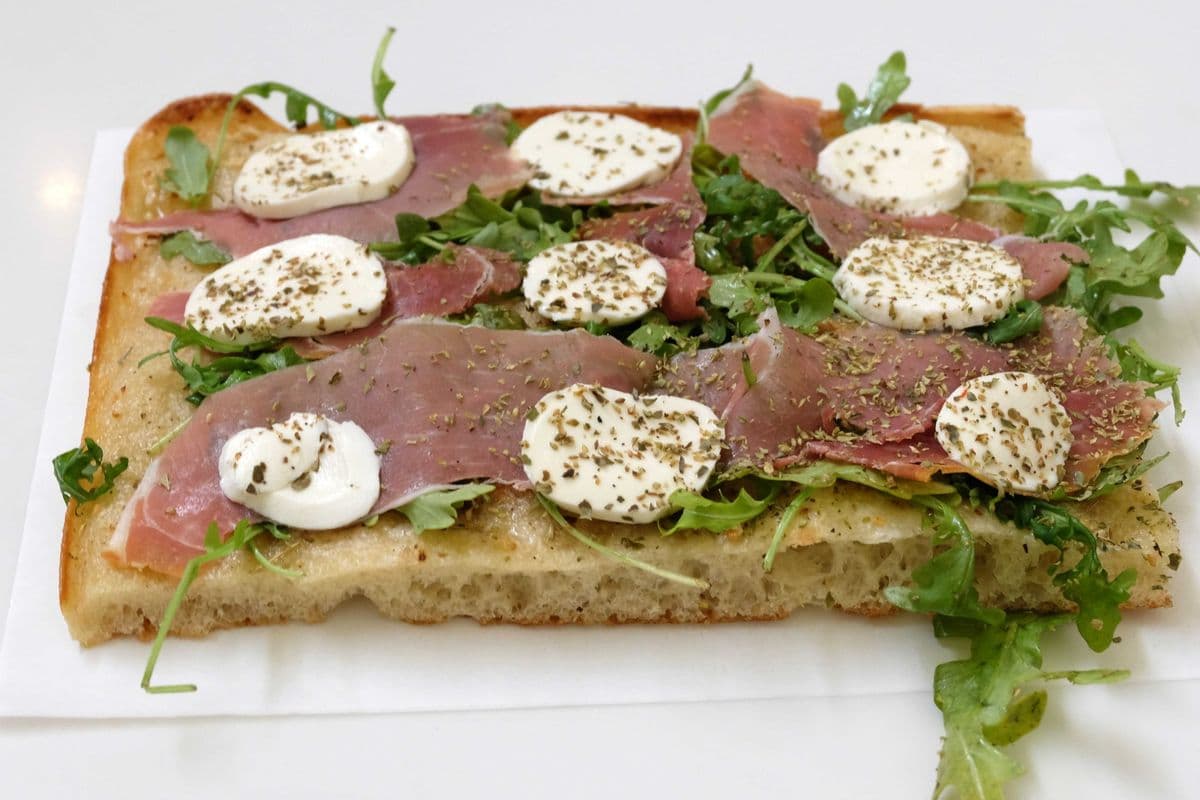 Pizza base à l'ail, prosciutto, roquette et fromage bocconcini