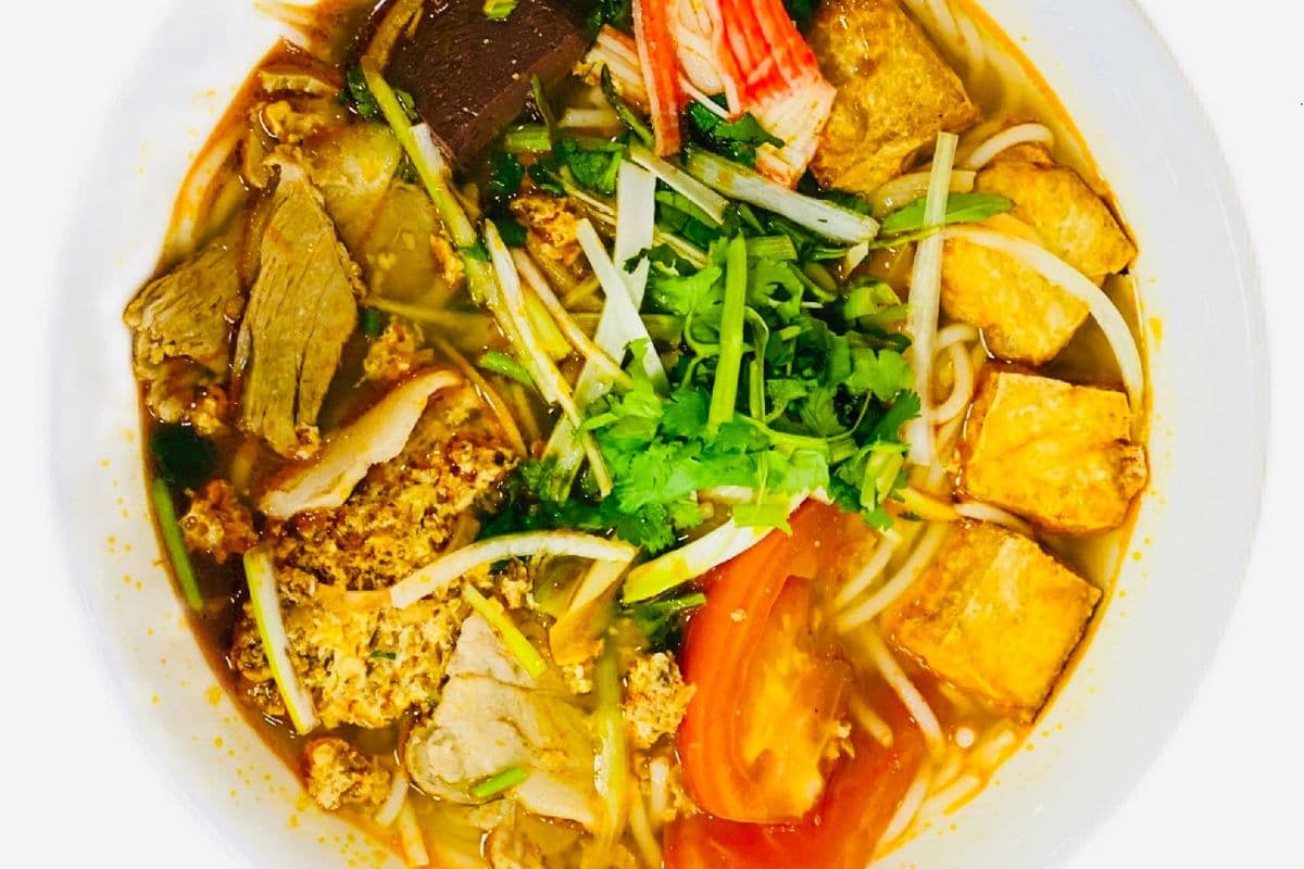 E2. Traditional Vermicelli in soup with fried tofu, crab meat, pork, and tomatoes.