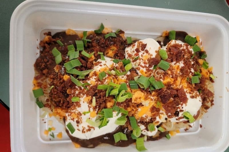 Six Potato Cheese Perogies Loaded with Shredded Cheese, Gravy, Bacon, Sour Cream, and Onions.